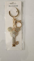 Gold key-shaped keychain with decorative elements on a white card with 'Blossom' branding.